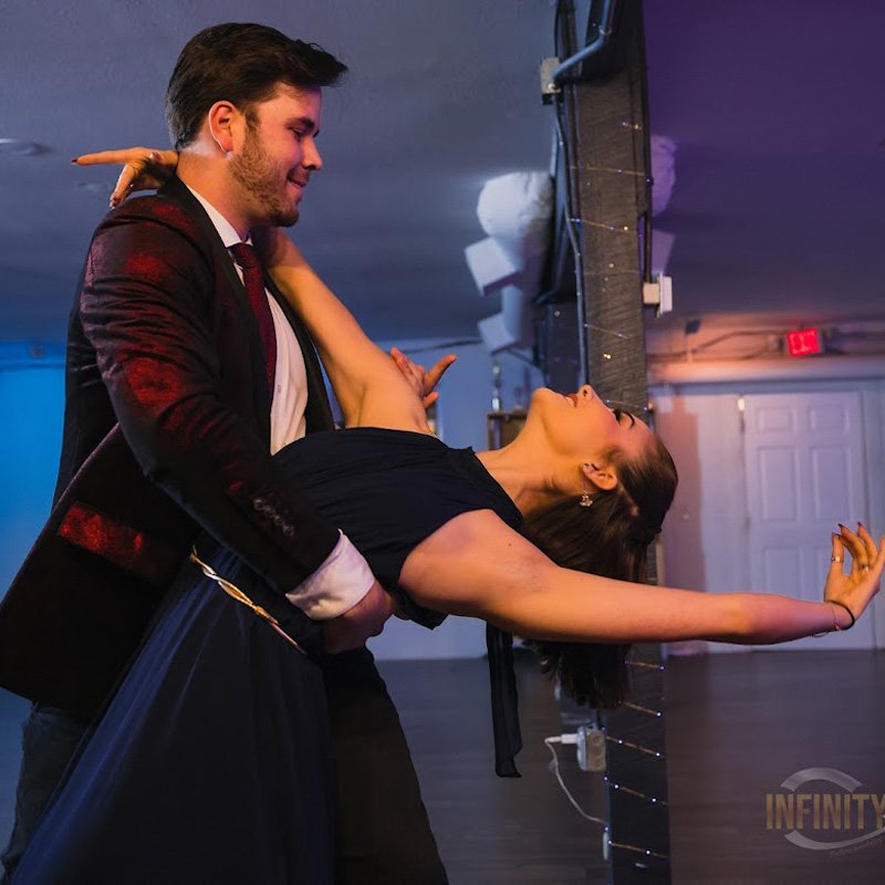 A man and woman practice ballroom dance steps in a bright Gainesville dance studio.