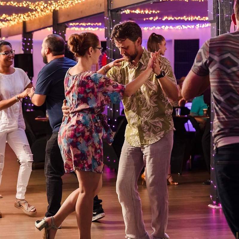 A diverse group of dancers in a club setting, engaged in social dance lessons in Gainesville, FL.