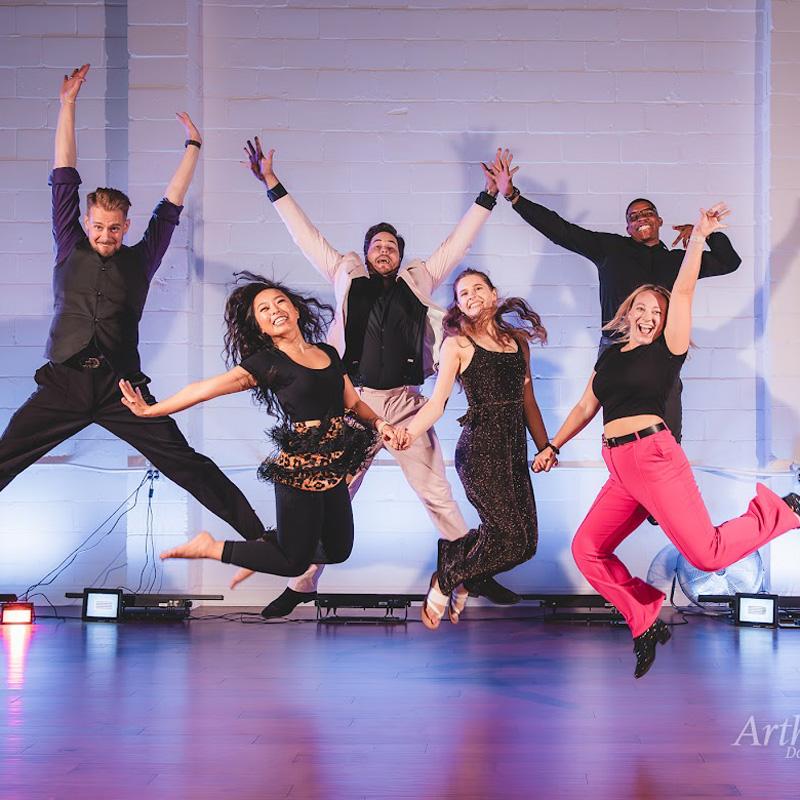A lively group of people jumping on stage during dance lessons in Gainesville, FL.