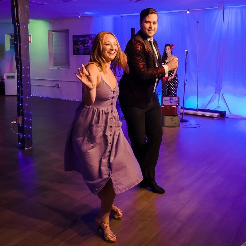 Joyful dancers in vibrant lighting in a studio, showcasing the benefits of dance in Gainesville, FL