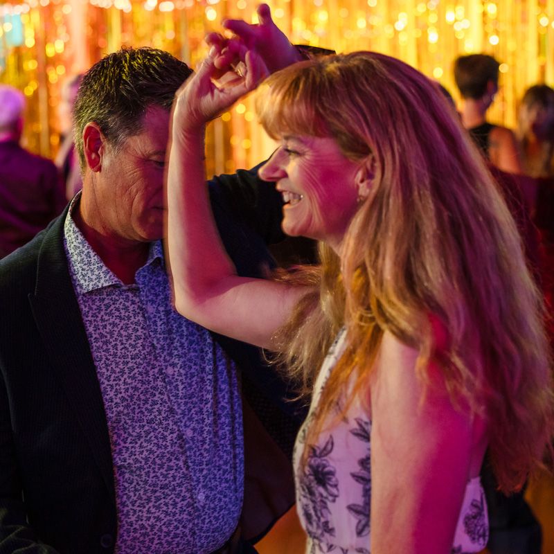 A man & woman dancing joyfully during dance lessons with warm lights & a festive vibe in Gainesville