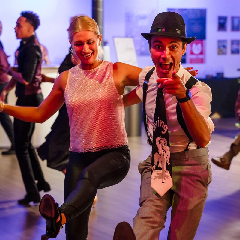 A lively swing dance duo mid-move, radiating joy under vibrant lights in Gainesville, FL