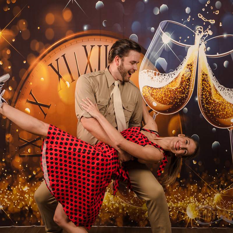 A couple swing dancing with a festive backdrop featuring a clock and champagne in Gainesville, FL