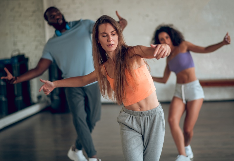 Three dancers practicing hip hop dance moves in a bright studio in Gainesville, FL